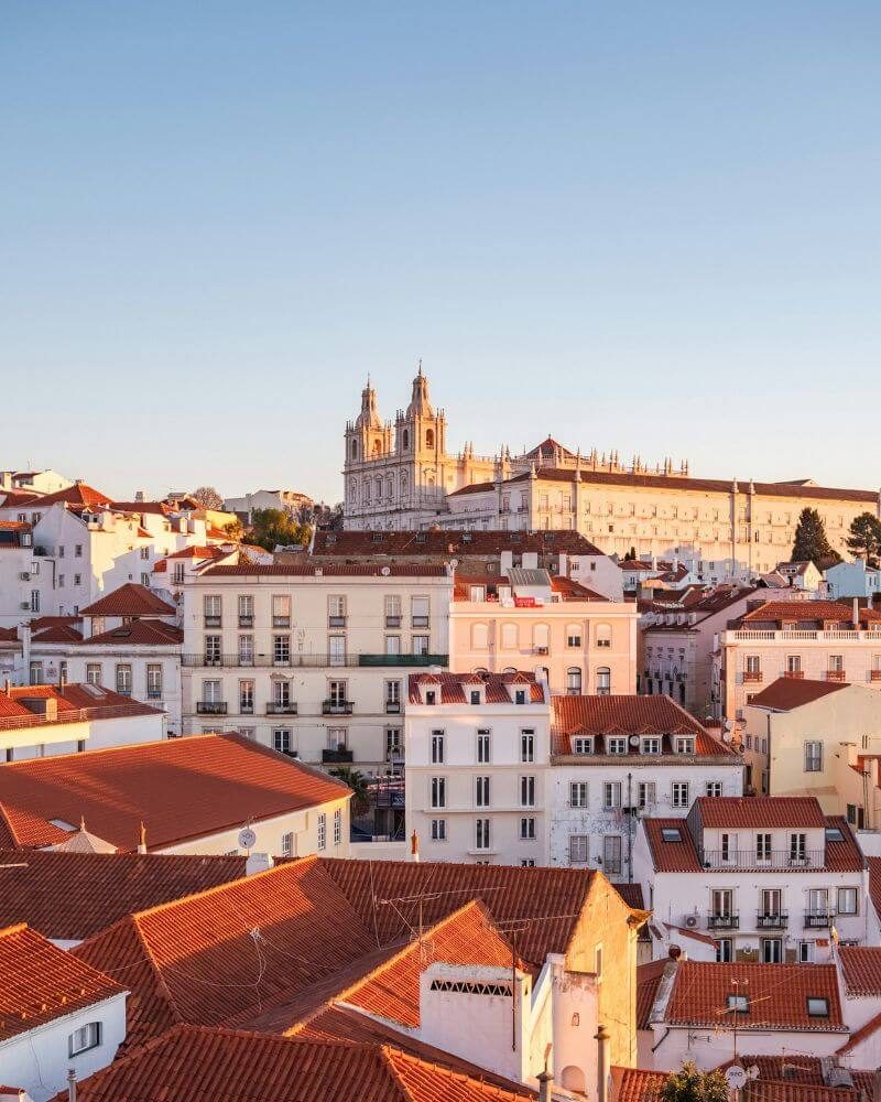 Lisbon's Alfama rooftops at golden hour, the monastery of São Vicente de Fora above